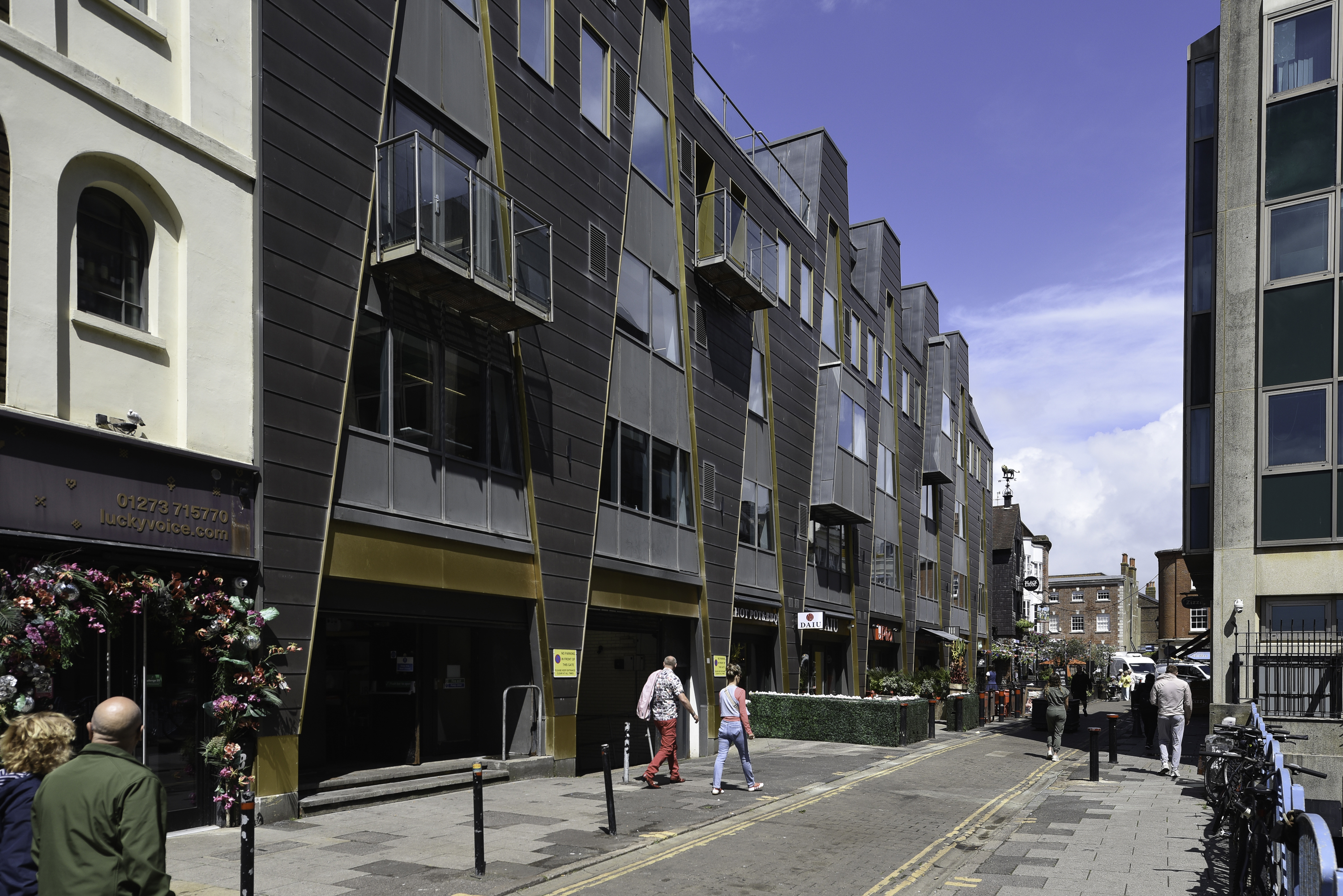 Street-level view down Black Lion Street of the Moore House facade with its distinctive gold A-frame supports and shopfronts